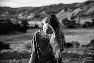 A young woman gazes down at the ground.