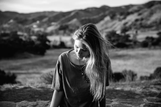 A young woman gazes down at the ground.