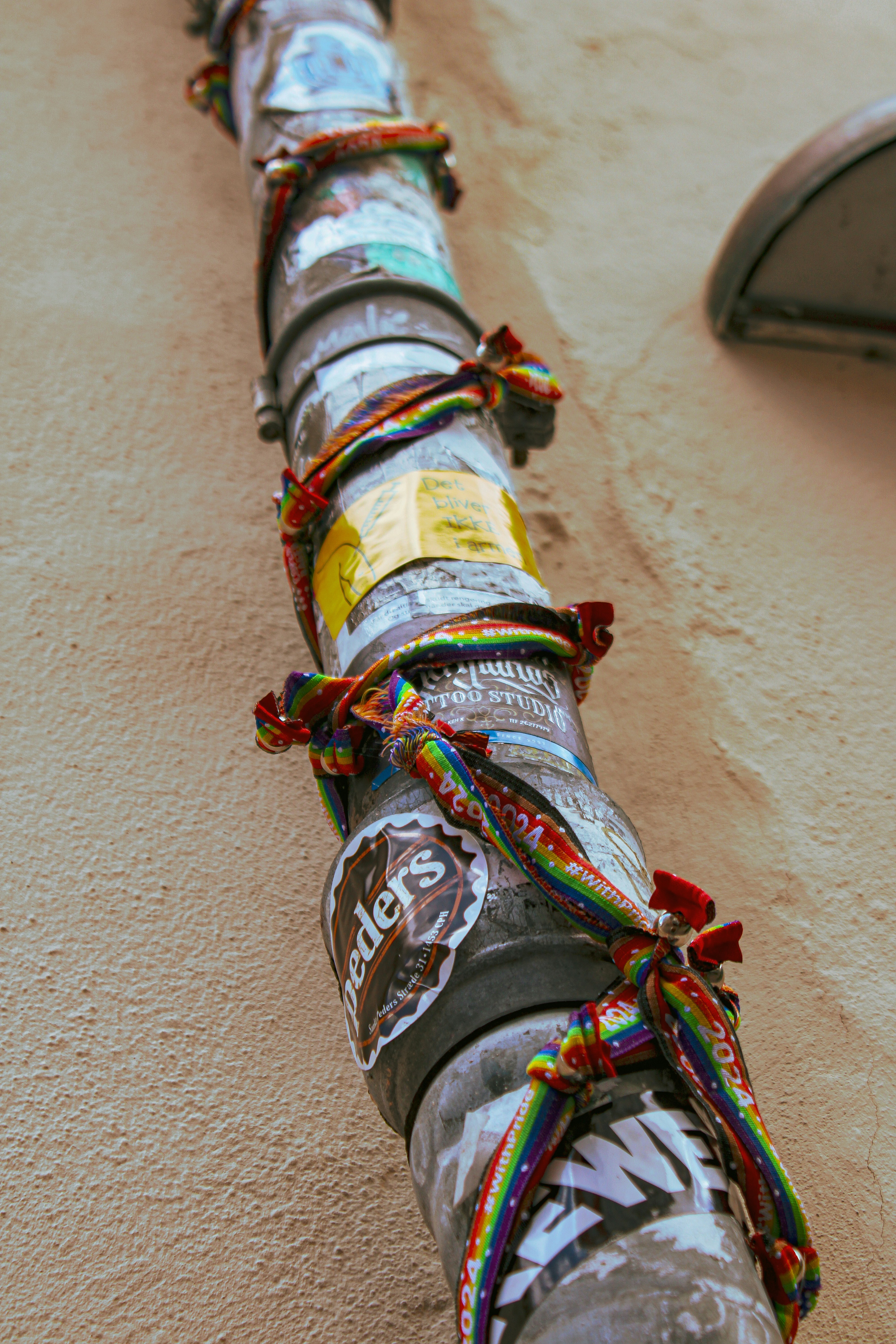 A downspout is decorated with stickers and ribbons.