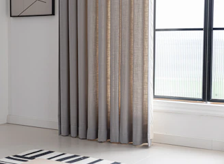 Curtains frame a window in a bright room.