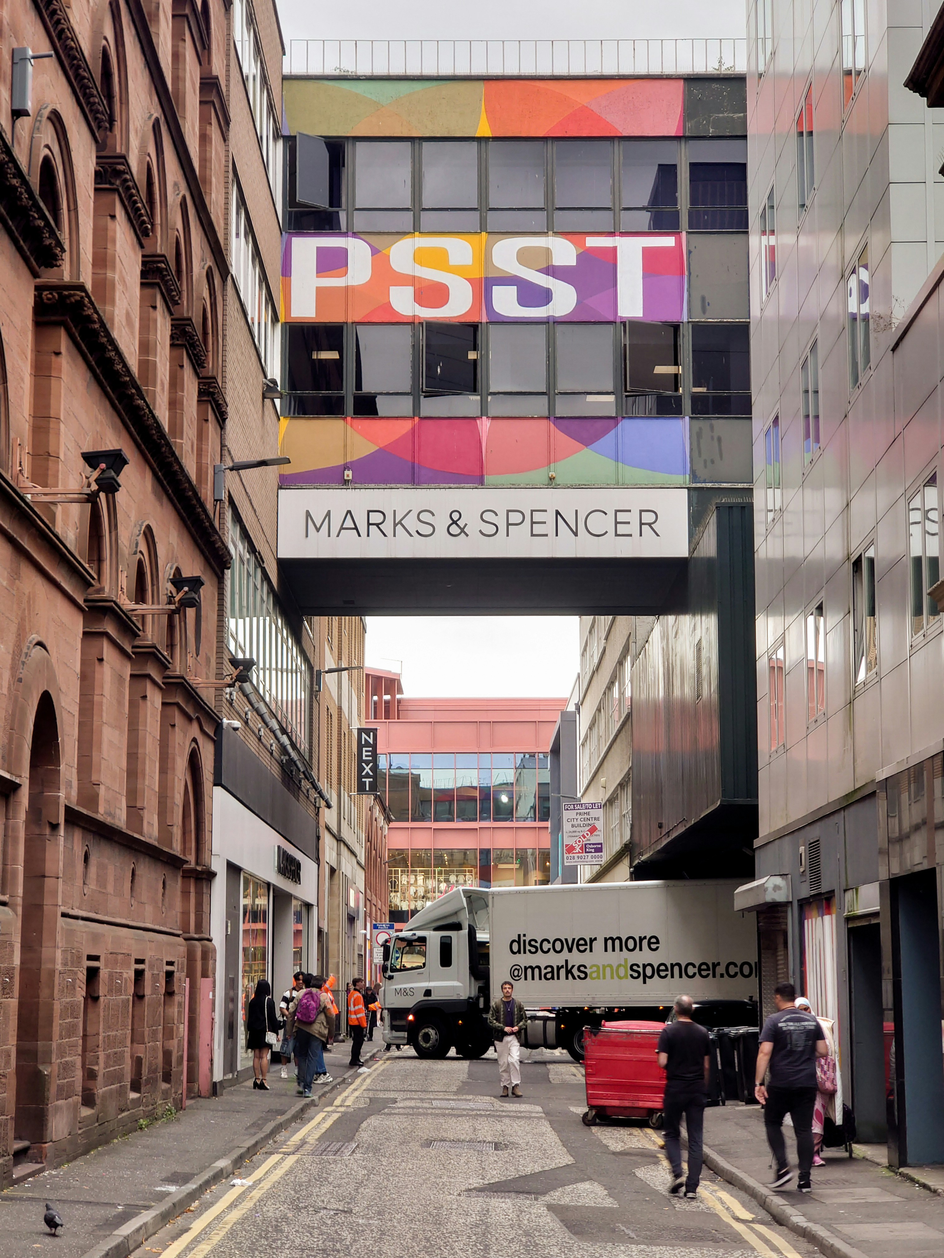 An alleyway in a city with marks & spencer signage.