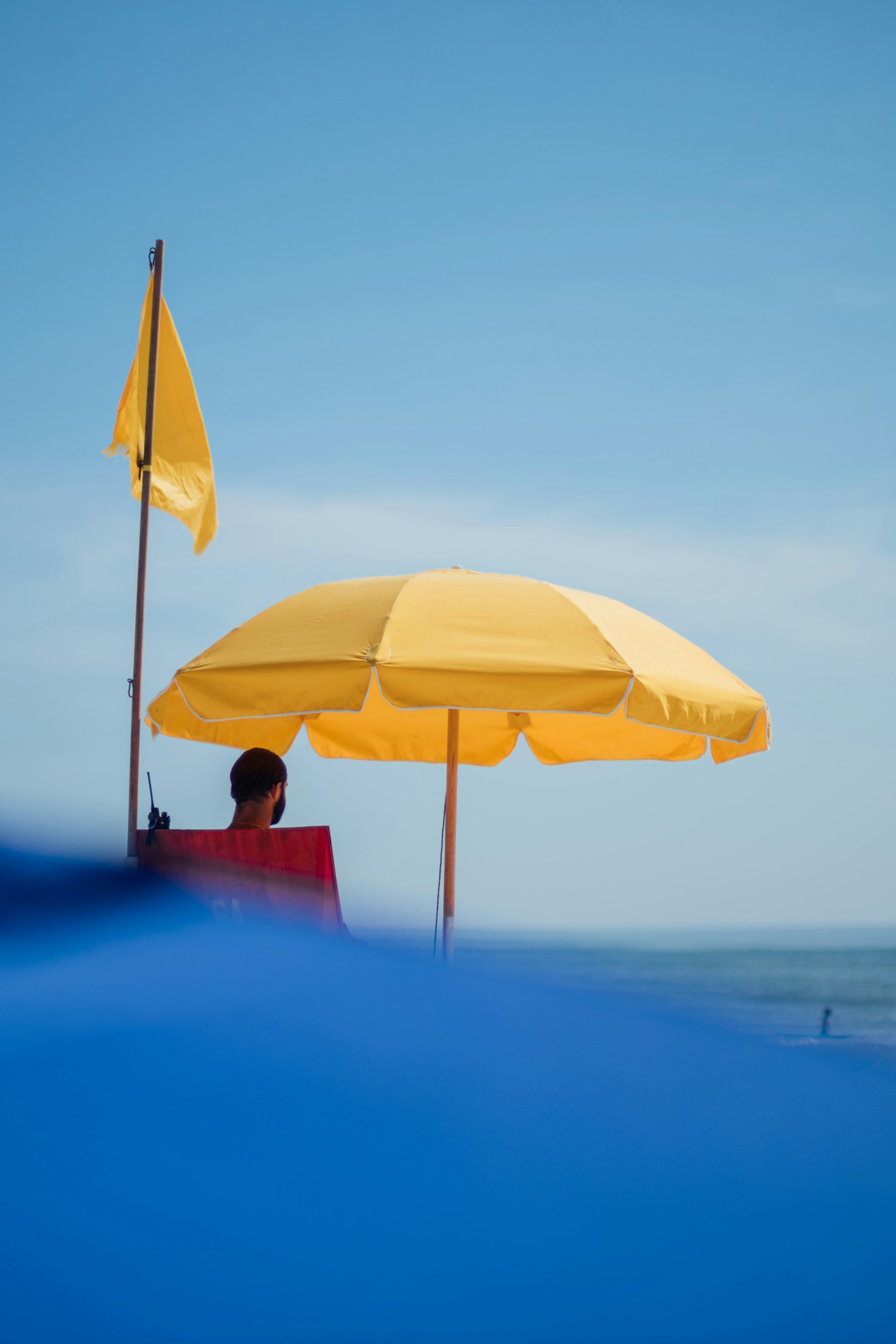 Un maître-nageur surveille la plage sous un parasol jaune.