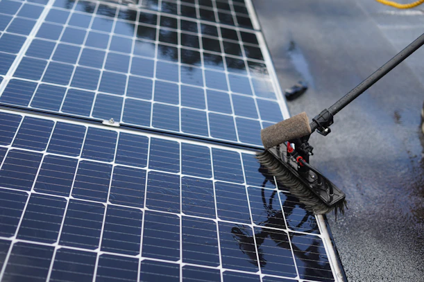 Cleaning solar panels with a long handled brush.