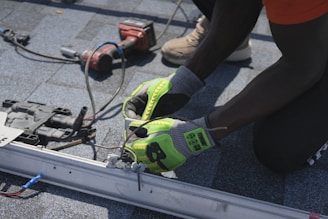 Worker installs electrical components on a roof.