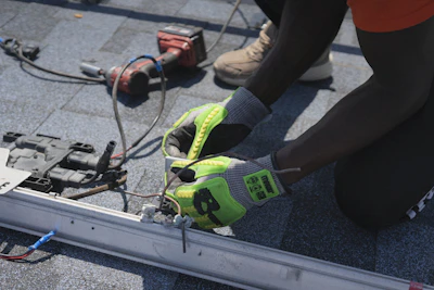 Worker installs electrical components on a roof.