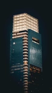Illuminated skyscraper at night against a dark sky.