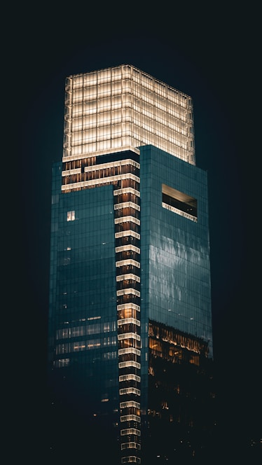 Illuminated skyscraper at night against a dark sky.