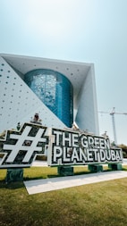 The green planet dubai sign is in front of a building.