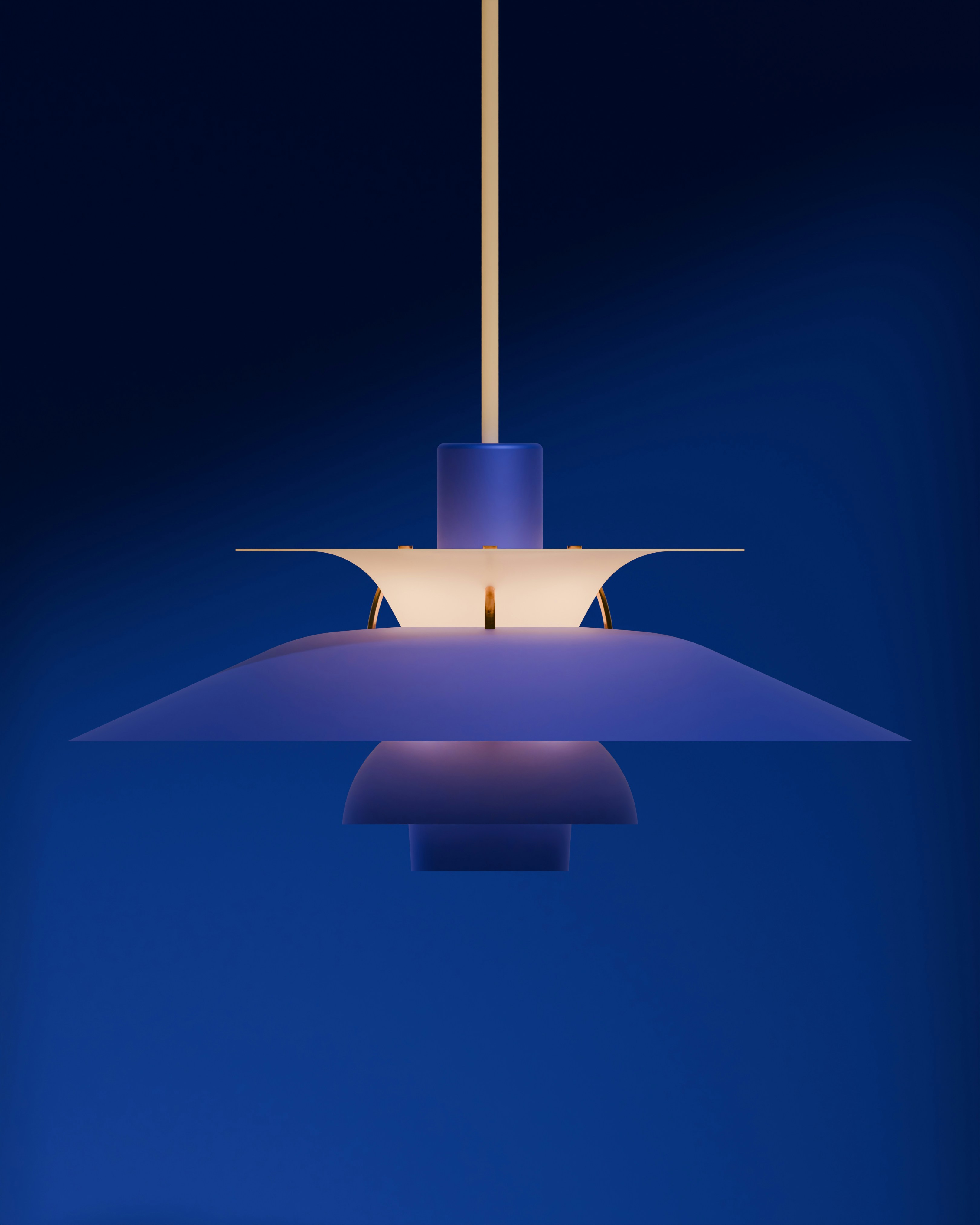A modern blue pendant light illuminated against the blue.