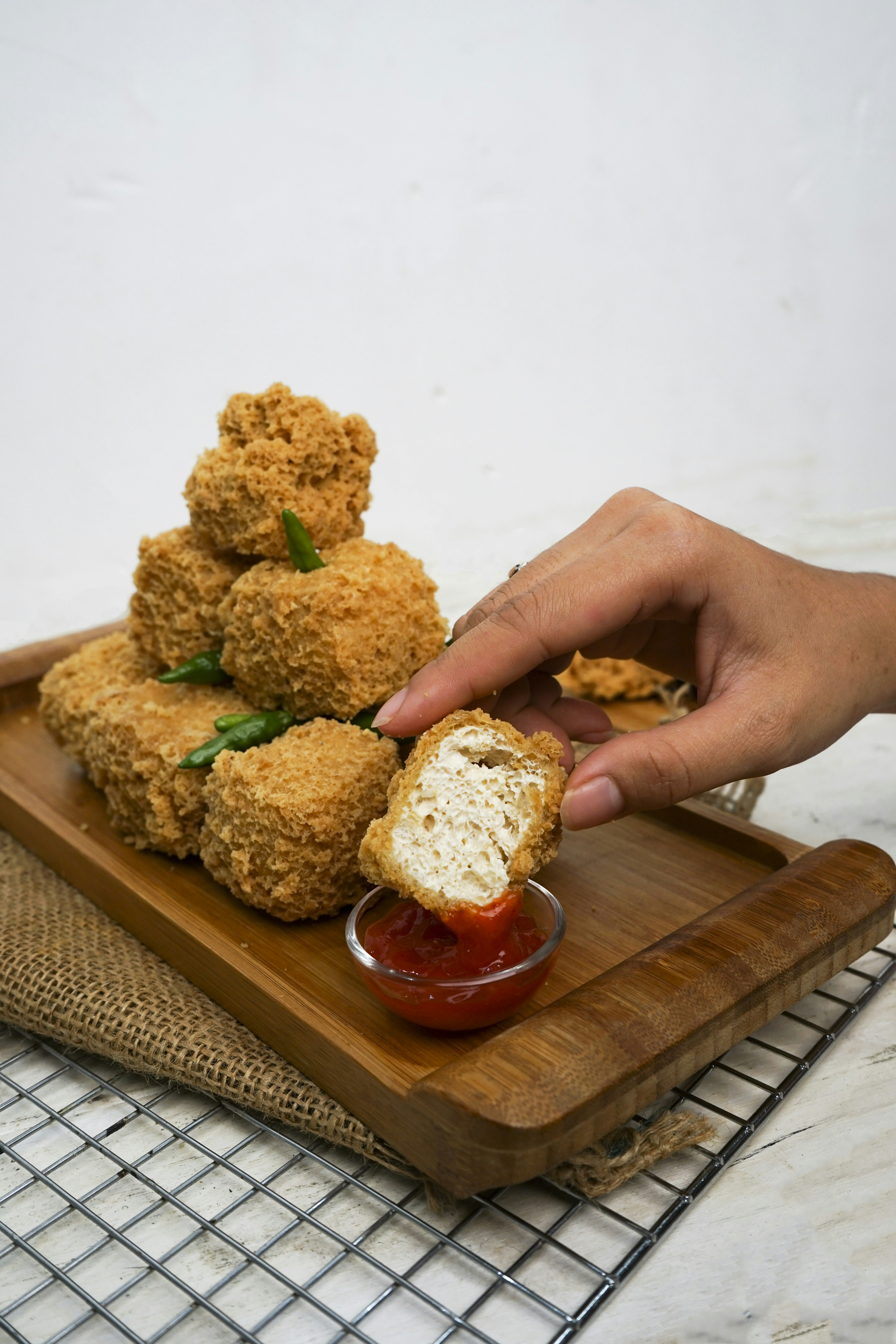 Tahu goreng dicelupkan ke dalam saus cabai merah yang lezat.