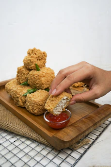Fried food being dipped into red sauce.