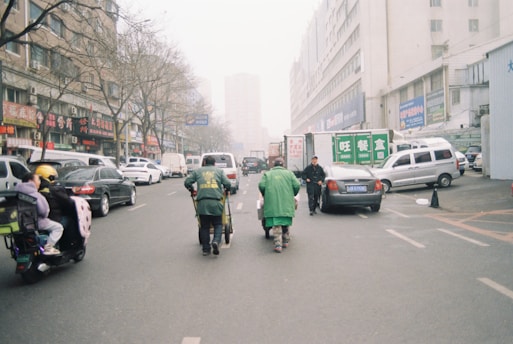 People ride scooters down a city street.