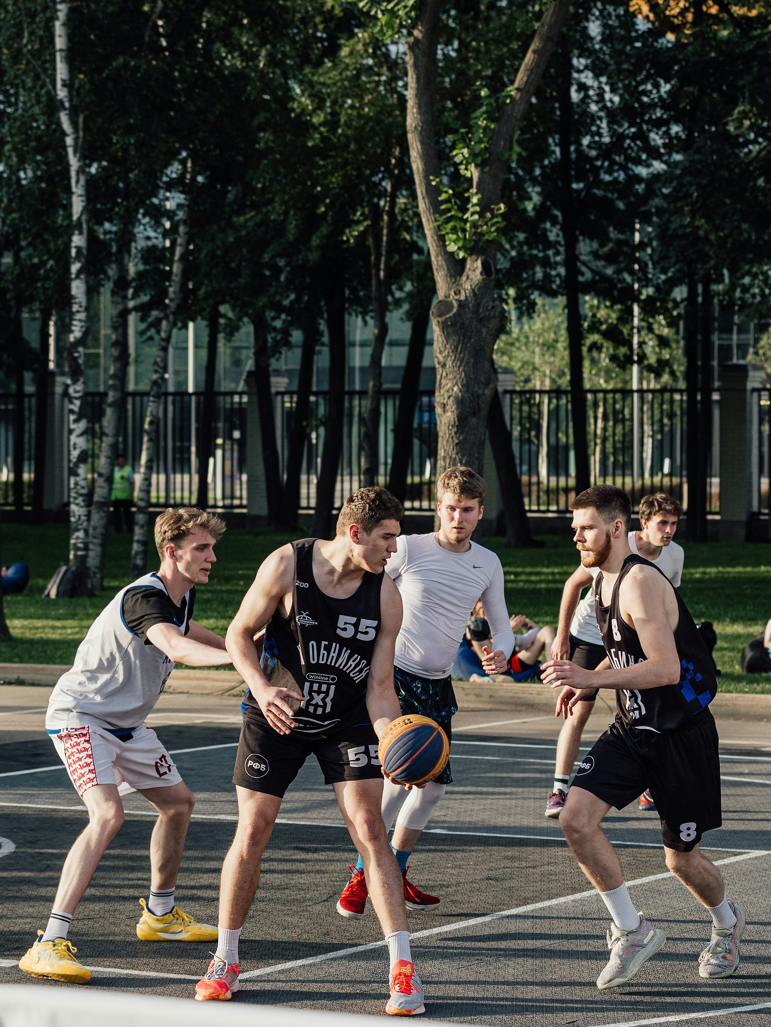 Pria bermain bola basket di lapangan luar ruangan.