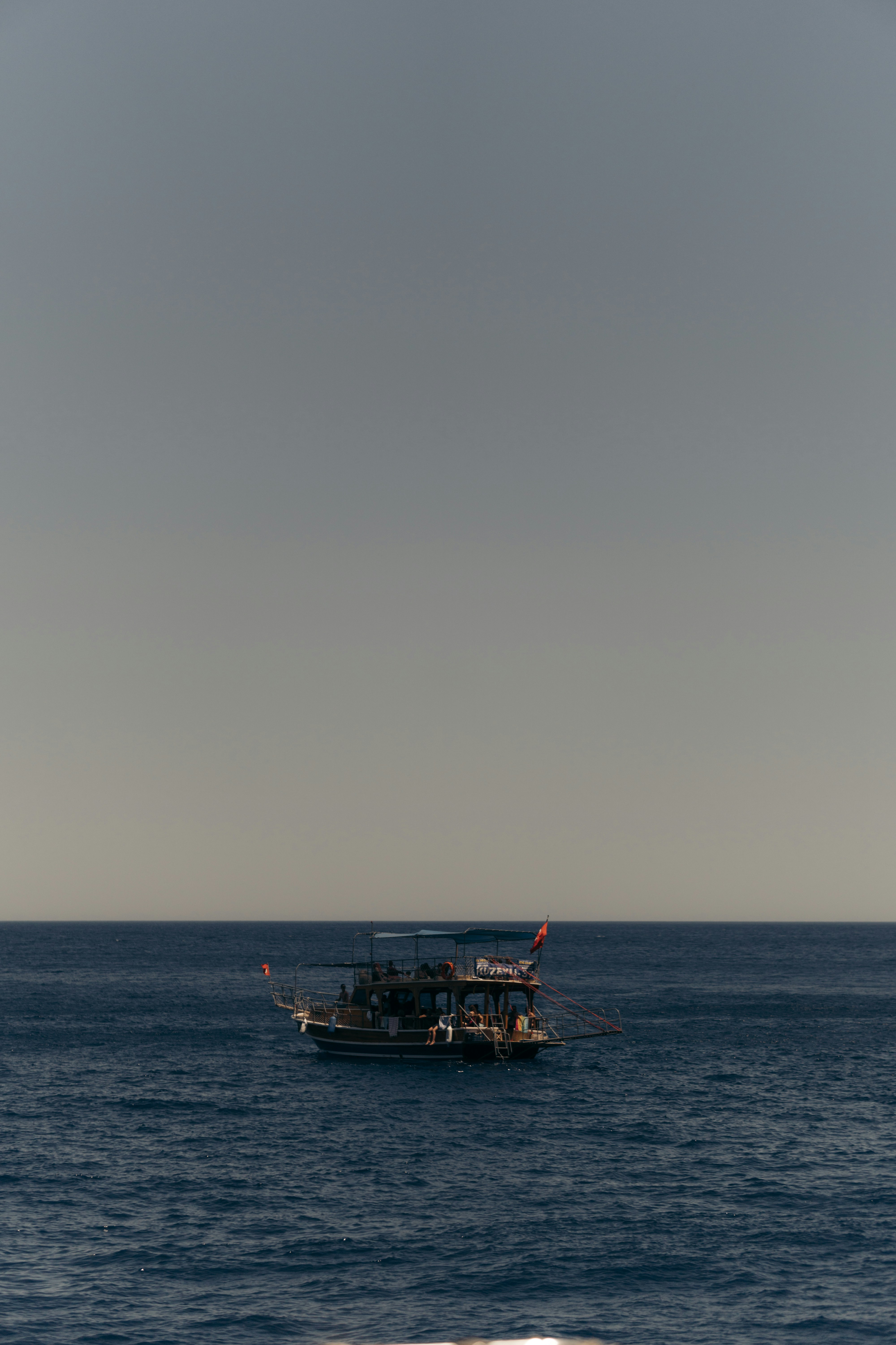 A boat sails on the blue ocean under a clear sky
