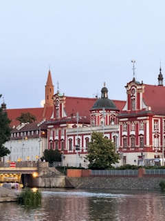 Ornate red and white buildings beside a calm river.