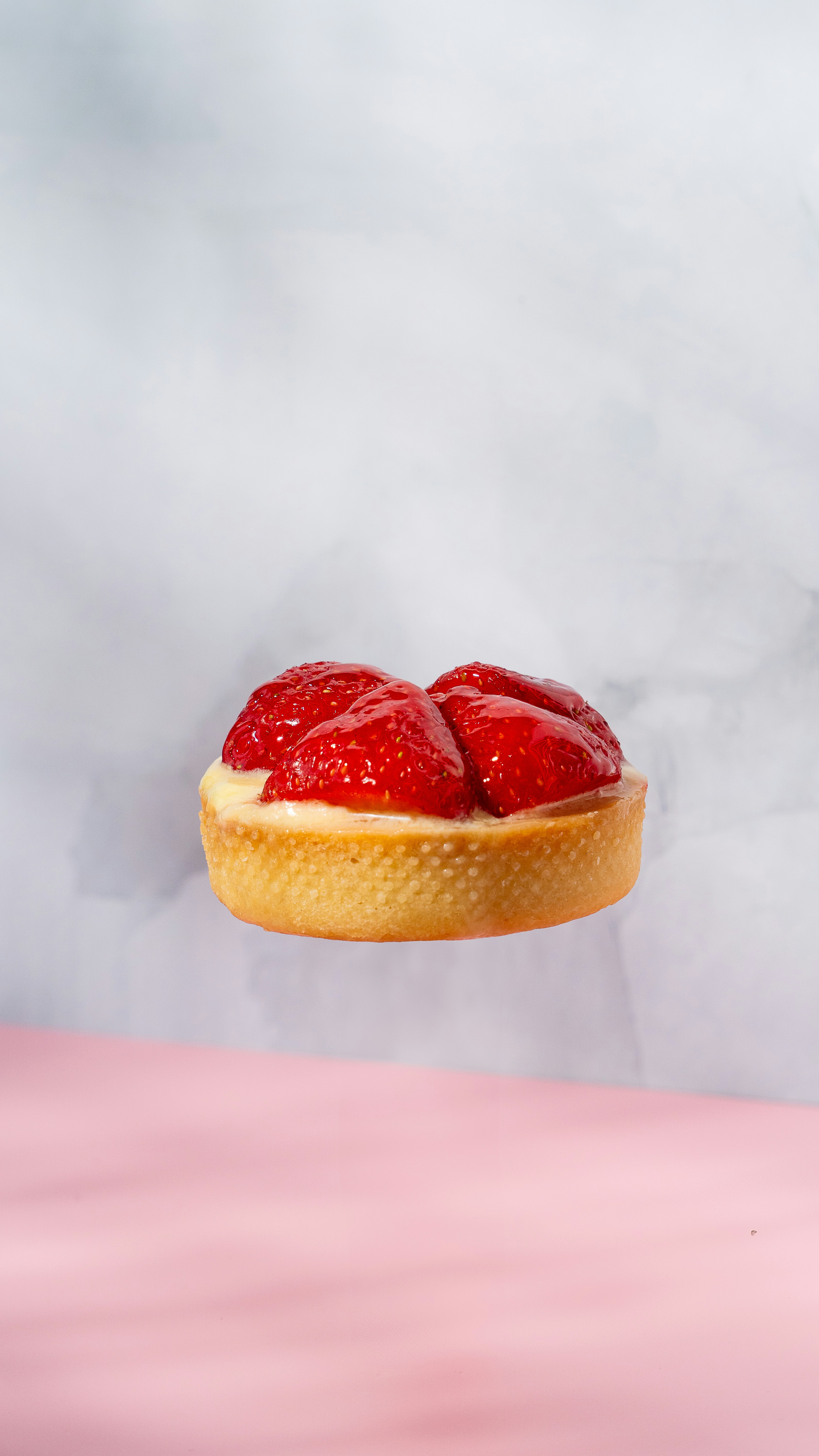 Une tarte aux fraises à la crème sur une surface rose