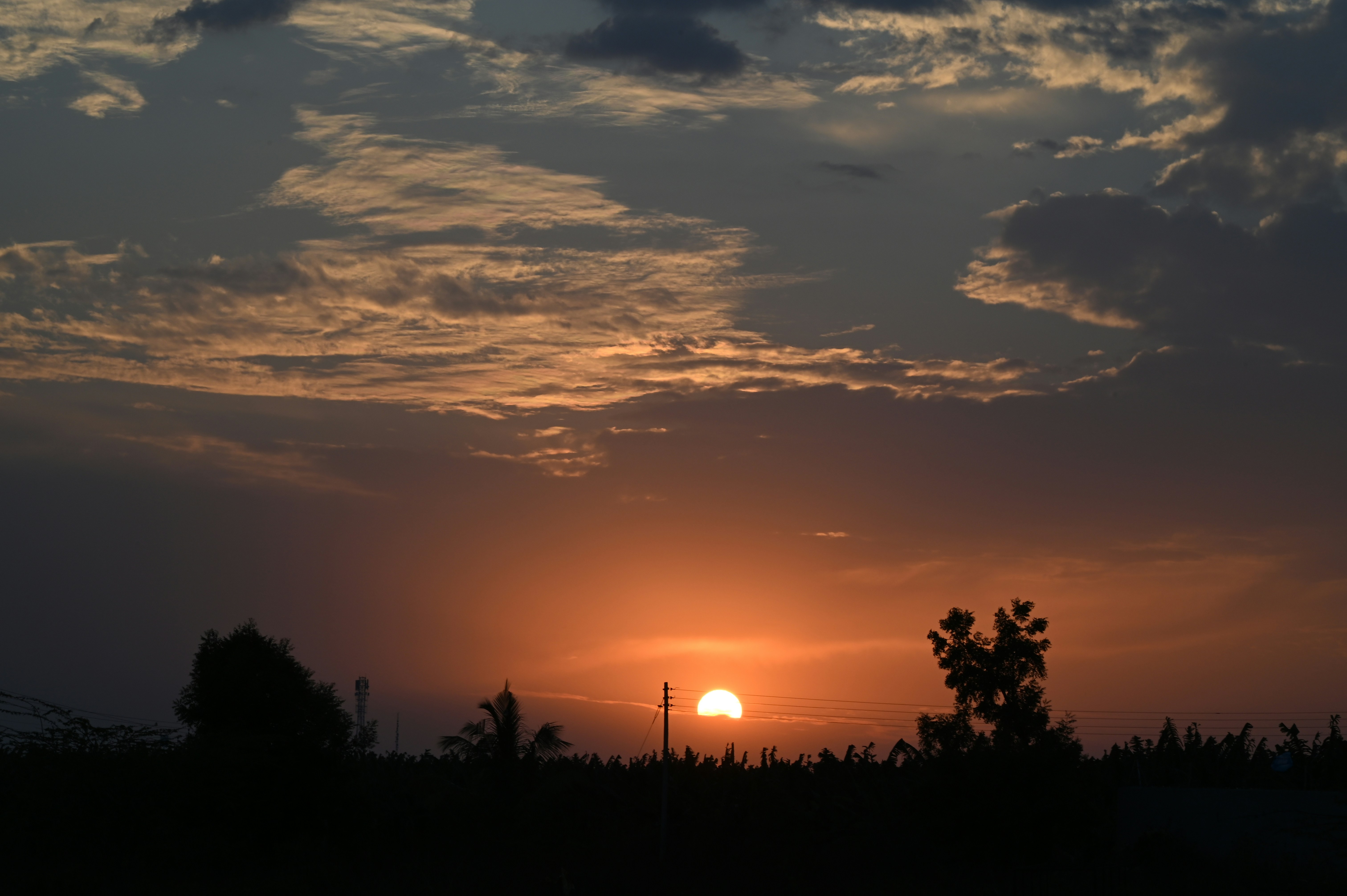 A person sitting calmly looking at a sunset over water.