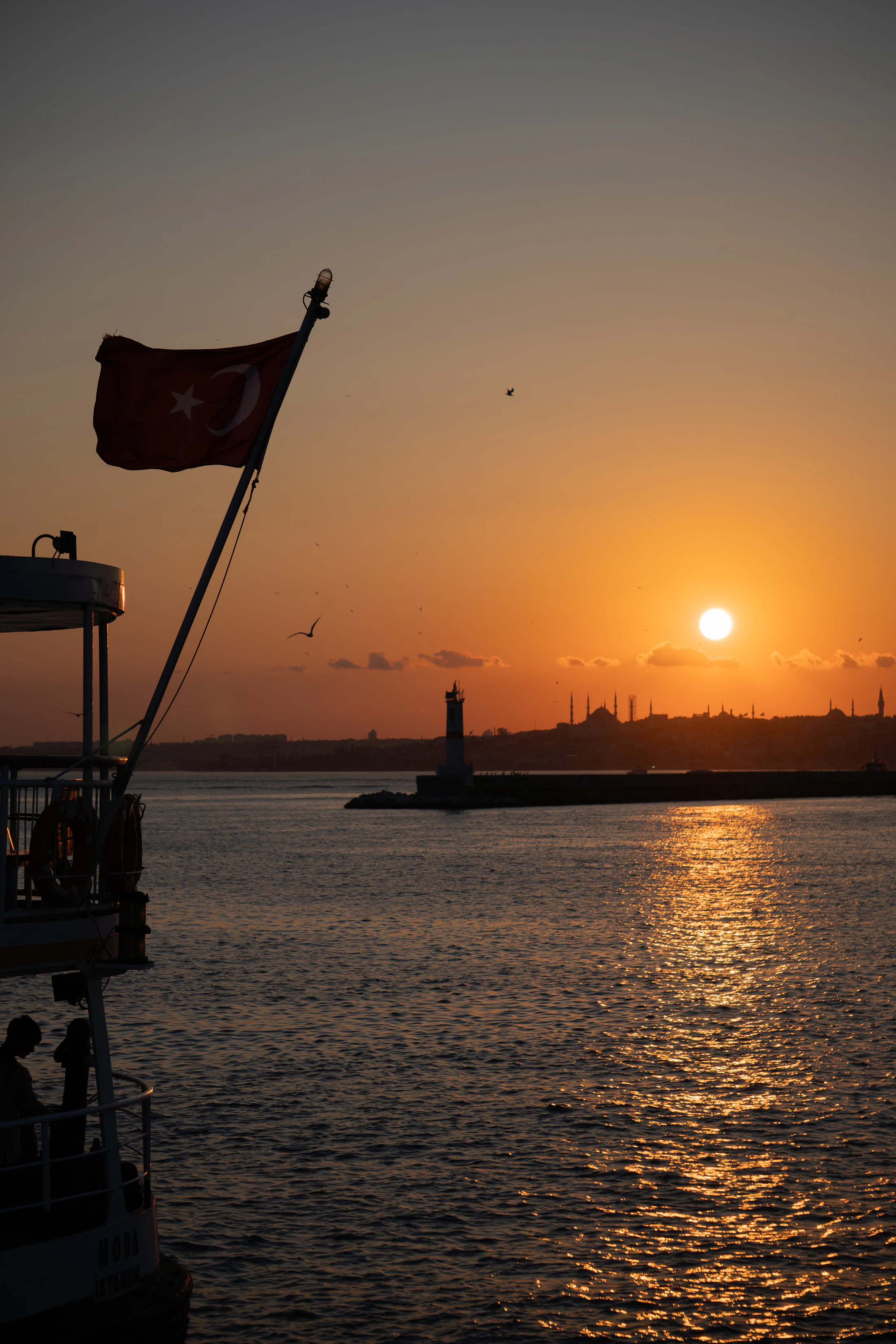 Turkish ferry and Istanbul skyline glowing at sunset across the Bosphorus