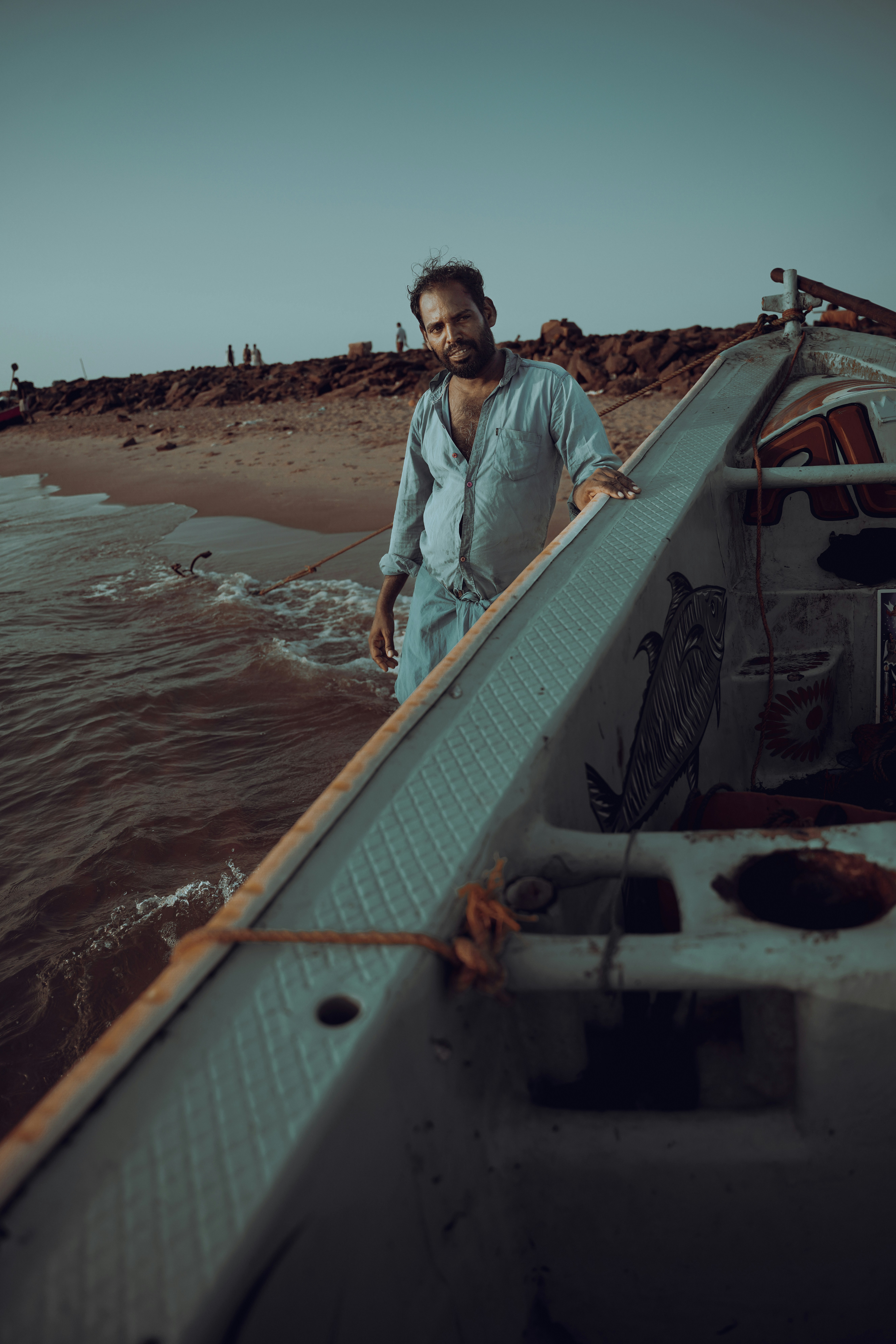 Man stands by boat on a sandy beach