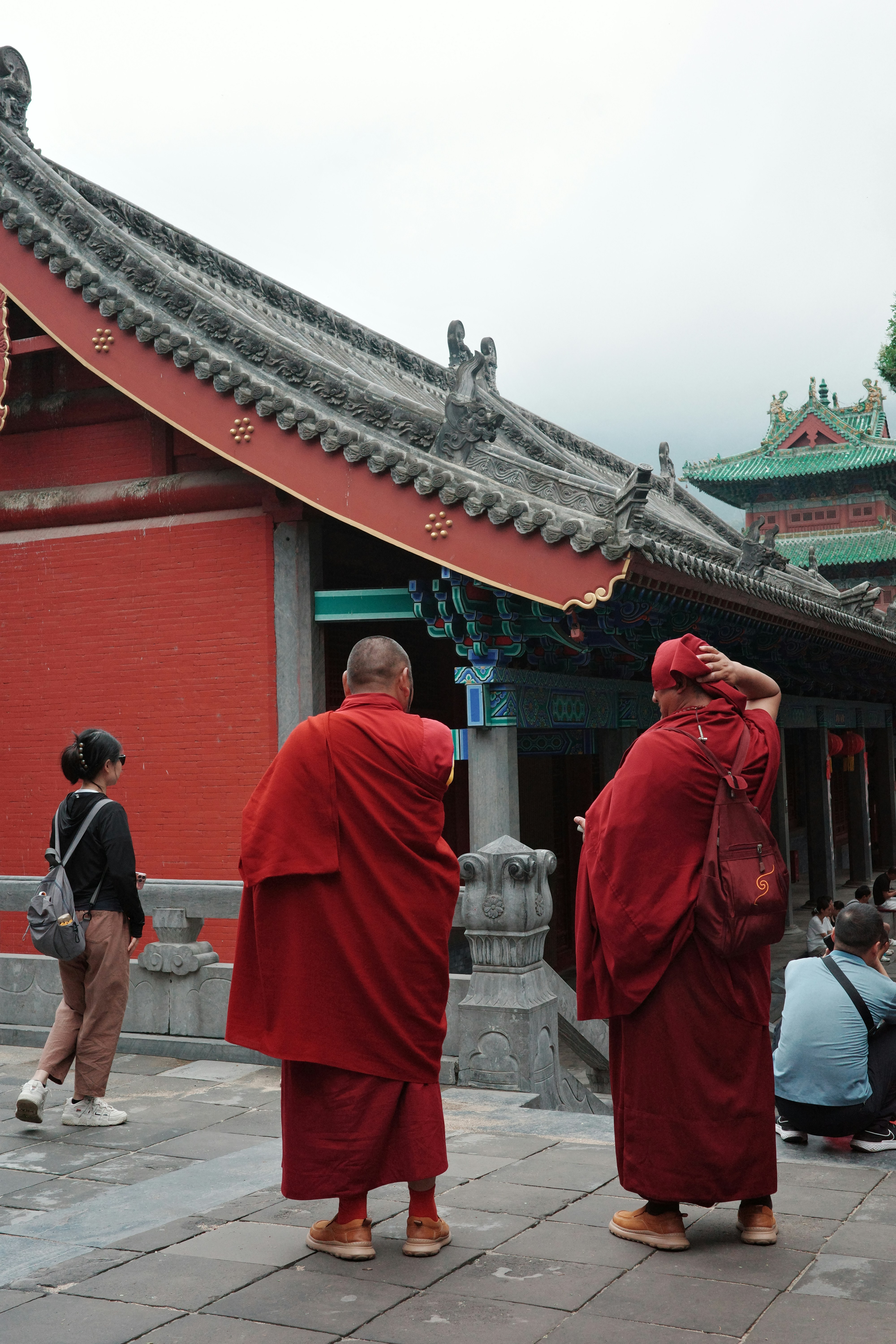 Two buddhist monks in red robes near a temple.