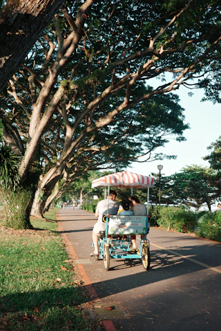 People ride a surrey bike along a paved path.