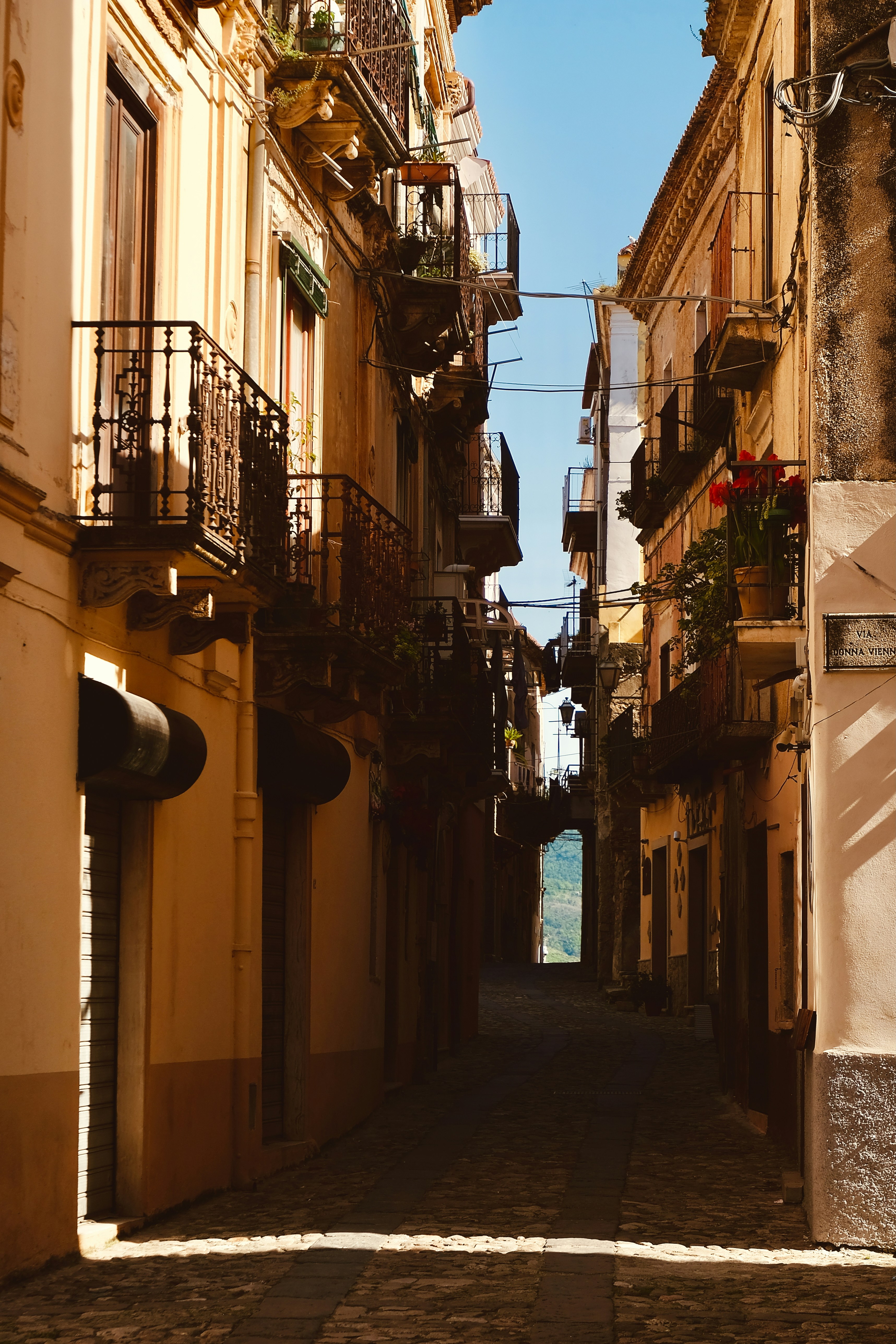 Narrow european street with balconies and blue sky.