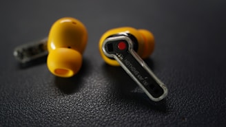 Two yellow earbuds with charging case on dark surface