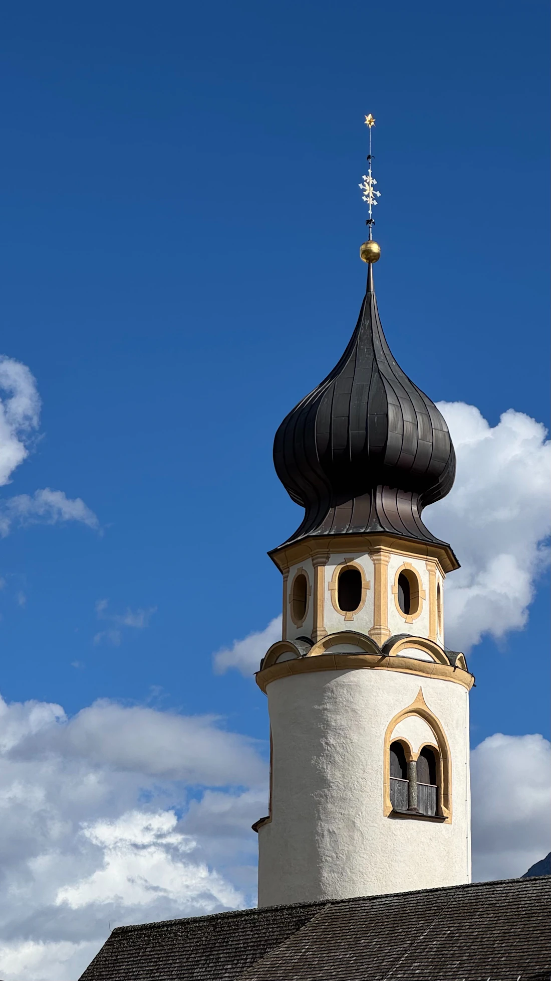 Kerktoren in San Candido tegen een blauwe lucht