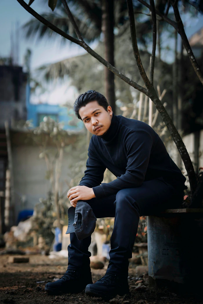 Man in a black turtleneck and jeans seated outdoors
