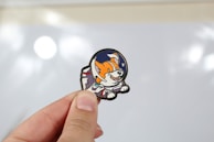 Hand holding a small cartoon cat pin