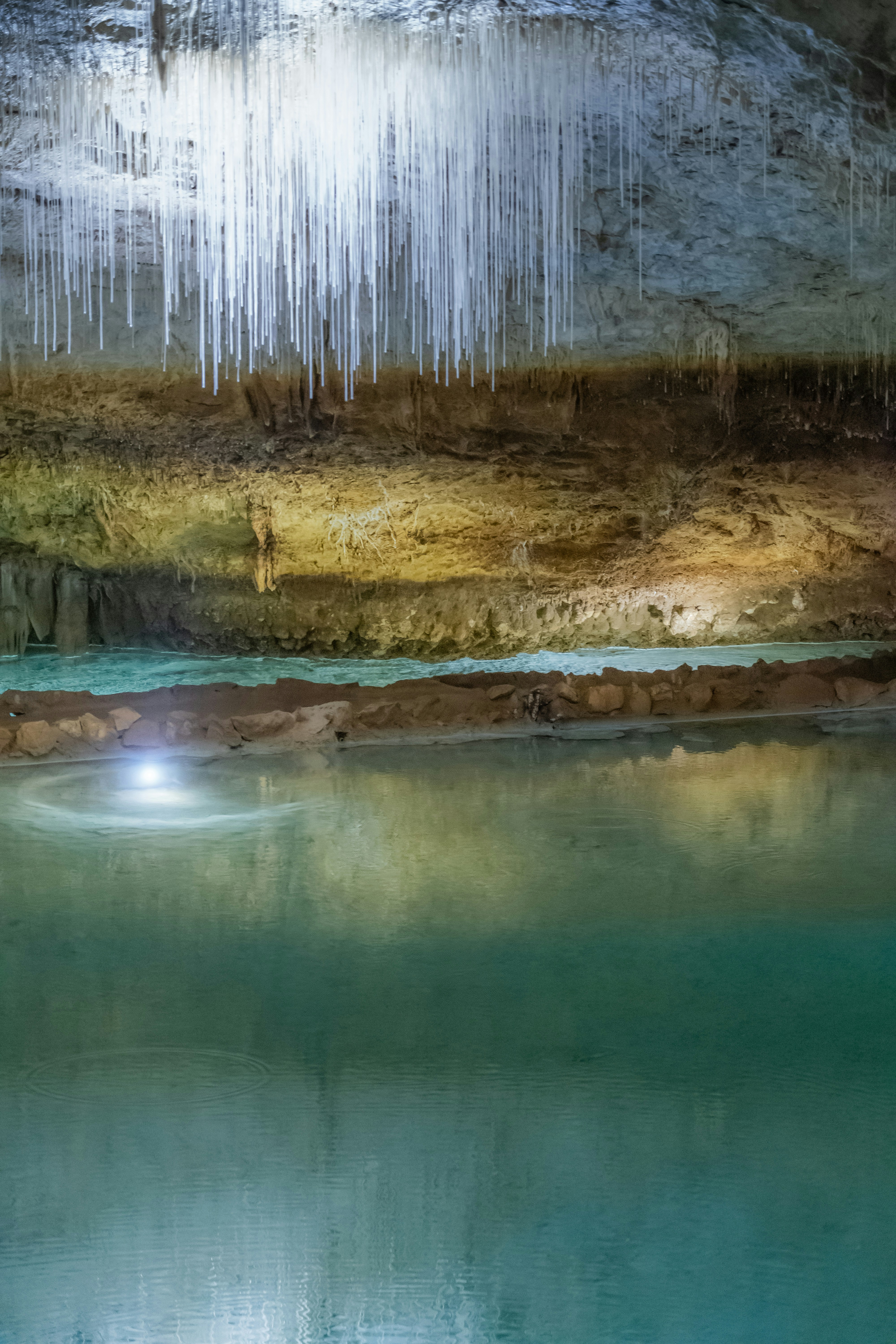 Cave ceiling with stalactites above turquoise water
