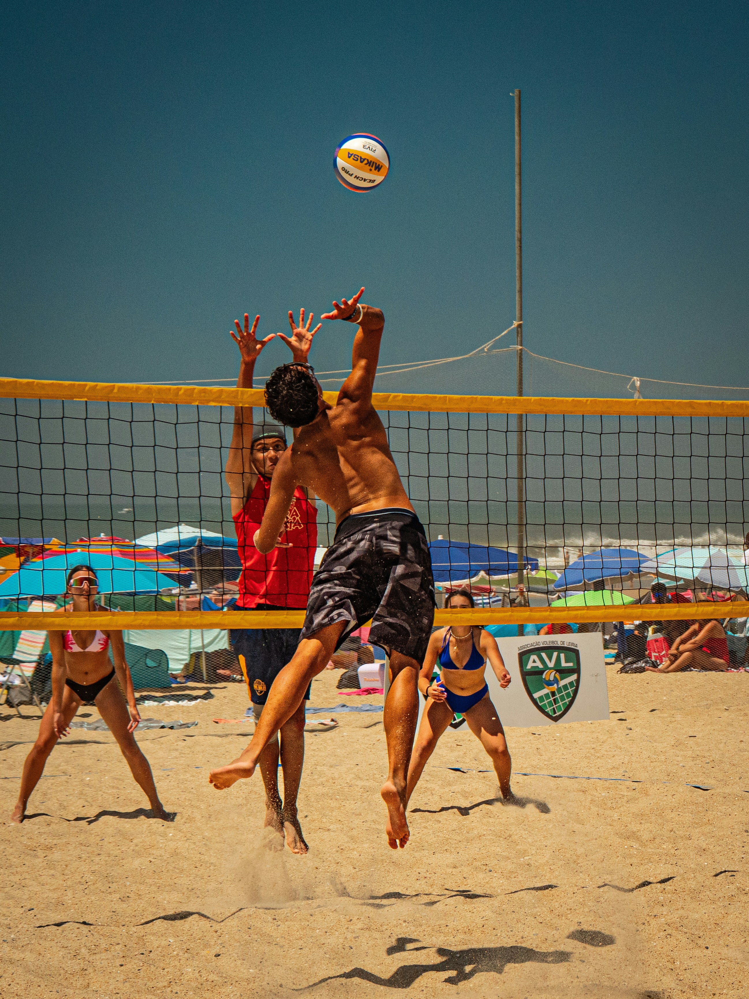 Giocatori di beach volley che saltano per colpire la palla