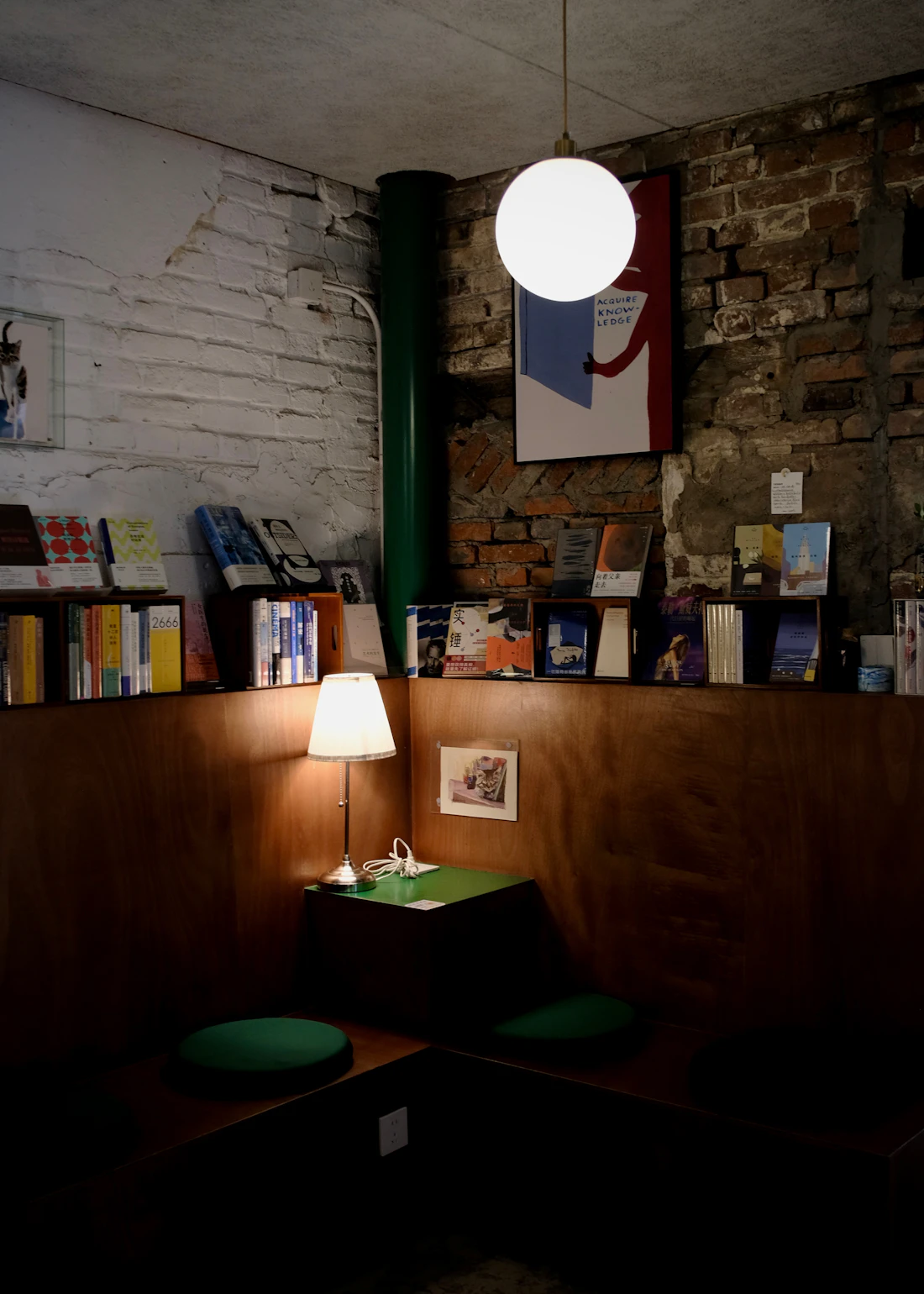 A cosy bookshop reading nook with warm lamplight and stacks of books
