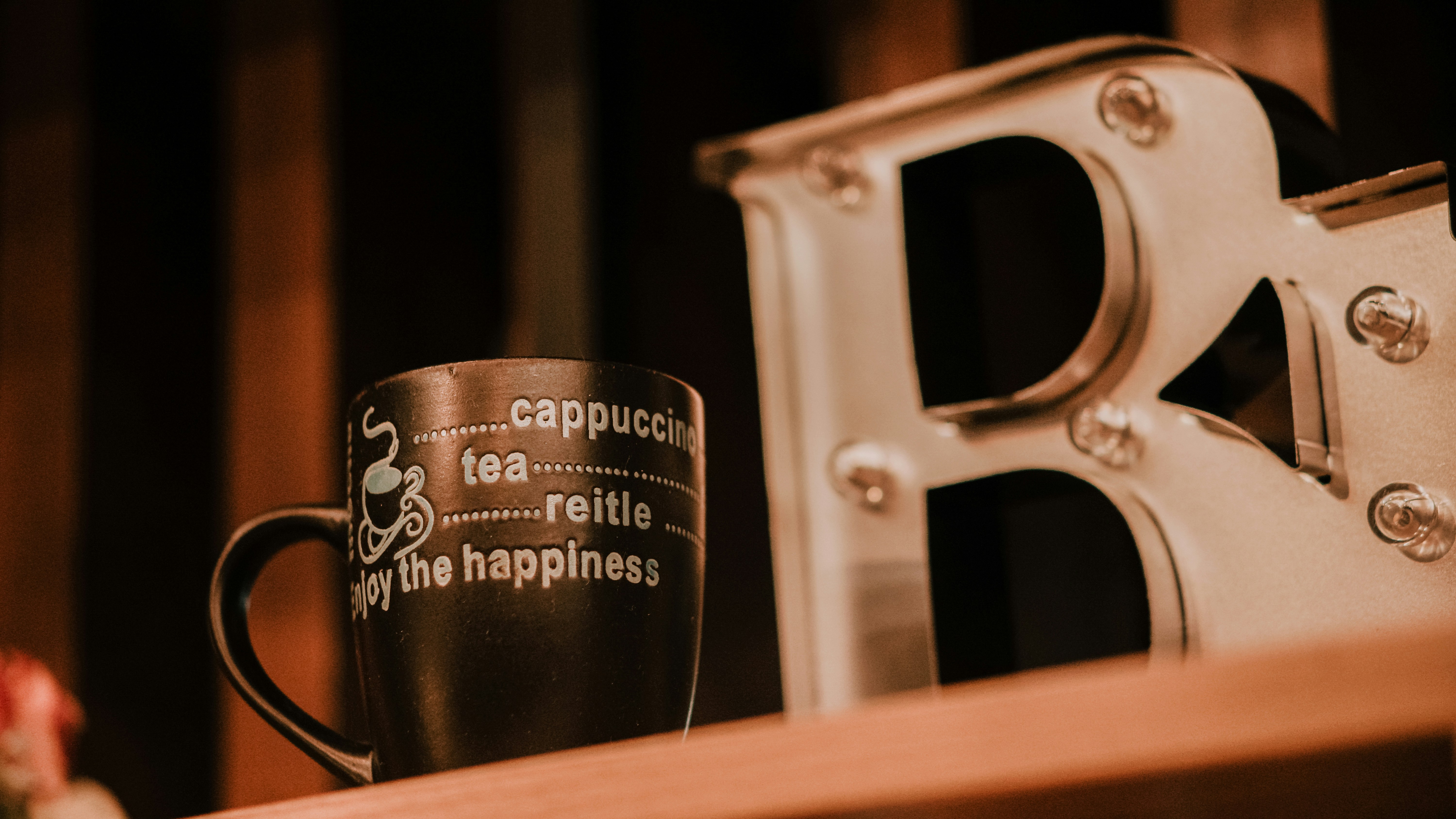 Una taza oscura se encuentra junto a una gran letra decorativa b.