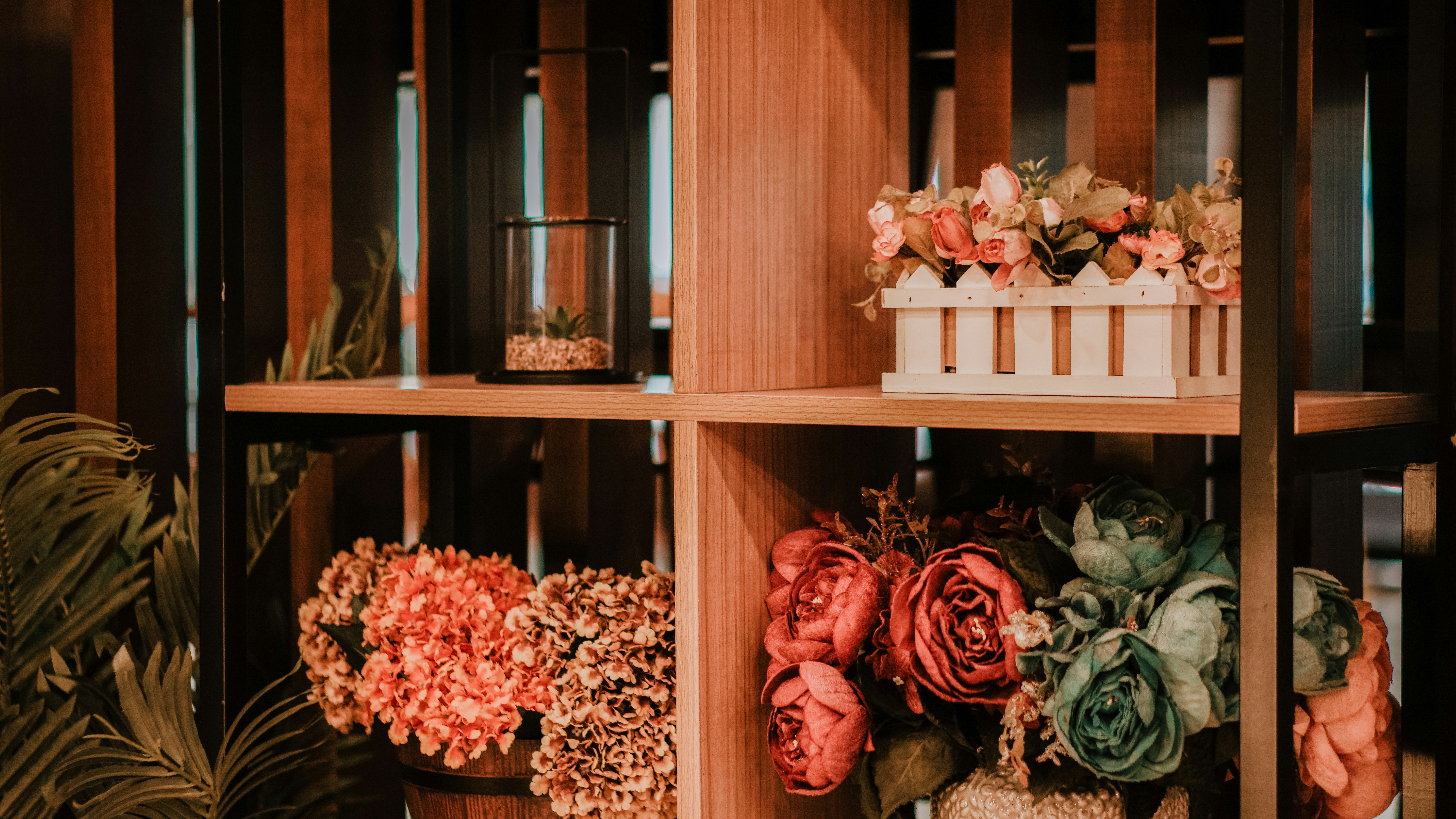 Los estantes de madera exhiben flores y plantas decorativas.