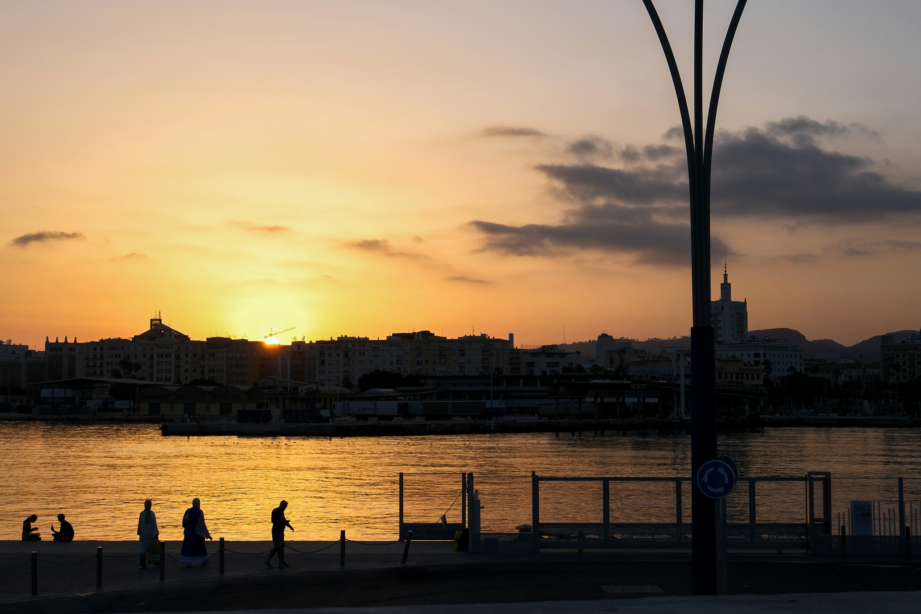 Sunset over calm water with city skyline silhouette