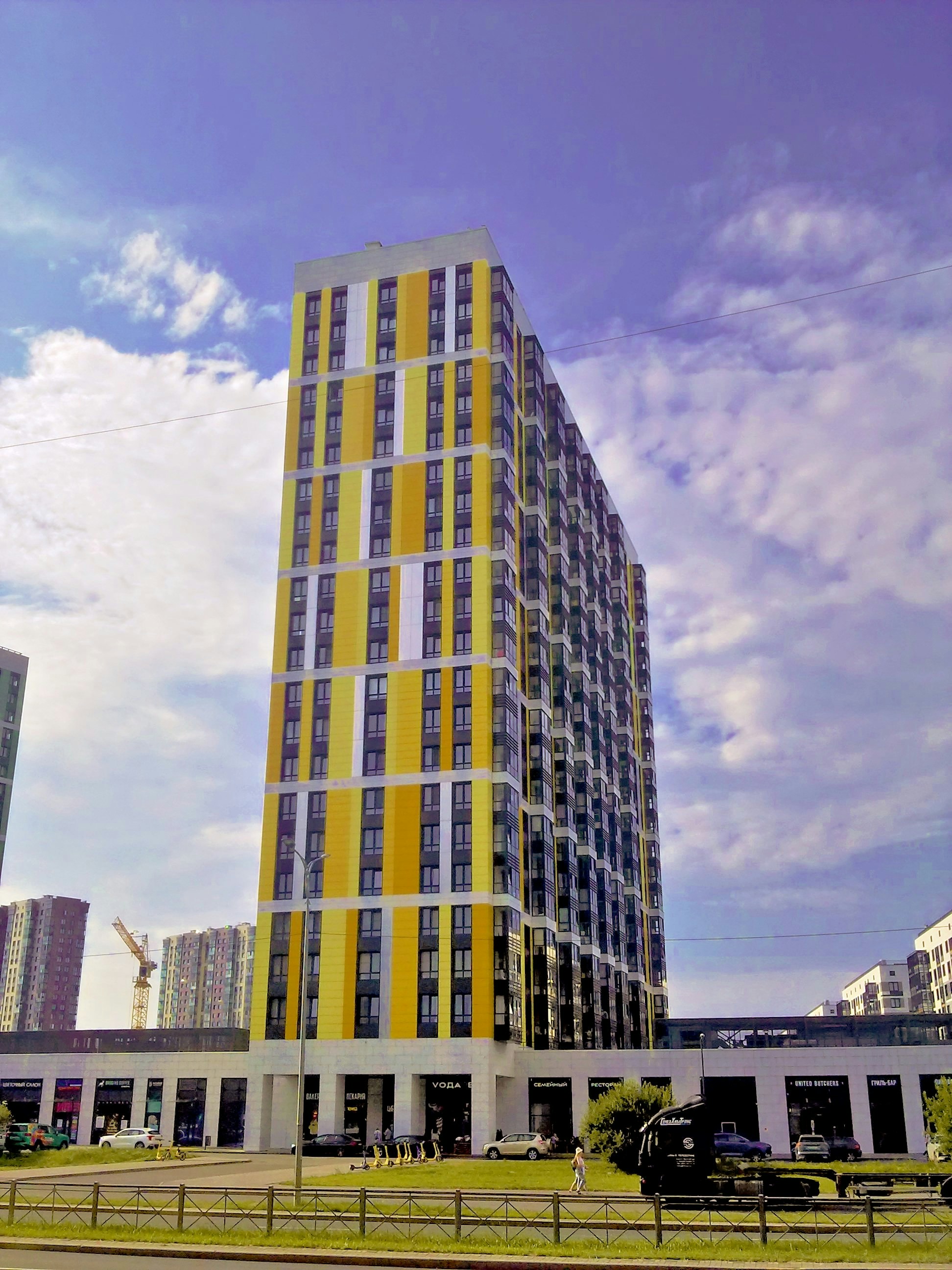 Modern high-rise building with yellow accents under sky.