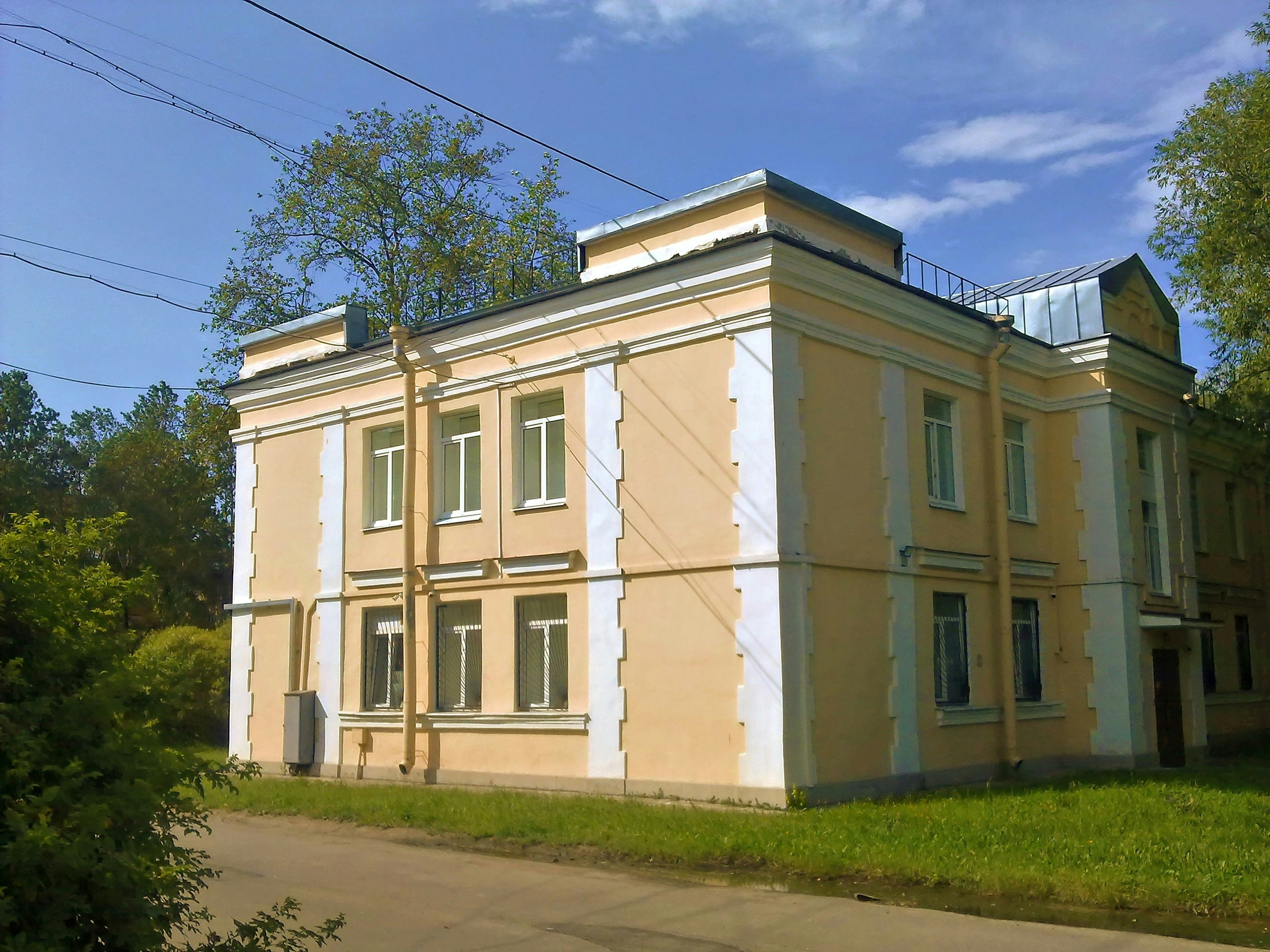 A light yellow building surrounded by trees