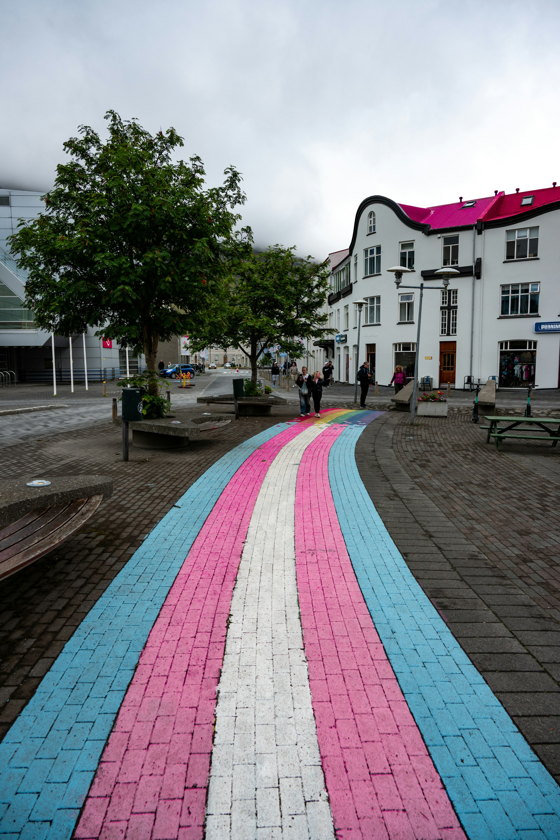 Colorful pathway leads to modern building with pink roof.