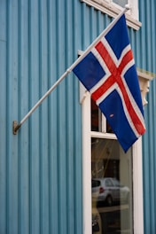 Icelandic flag flying on a blue wooden building.