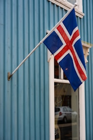 Icelandic flag flying on a blue wooden building.
