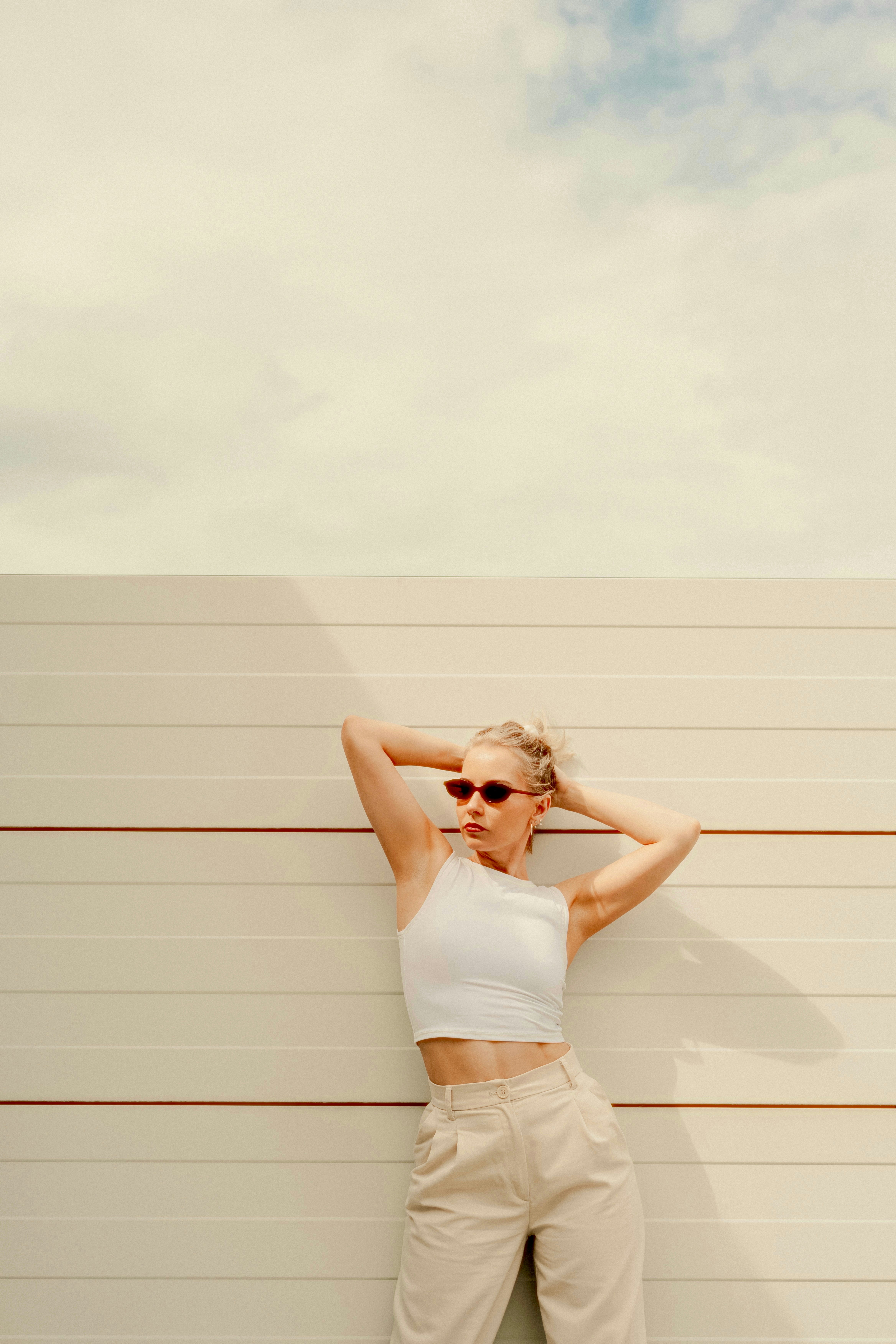 Woman in sunglasses poses against a wall