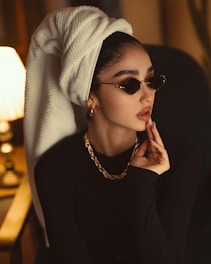 Woman with towel on head wearing sunglasses and necklace