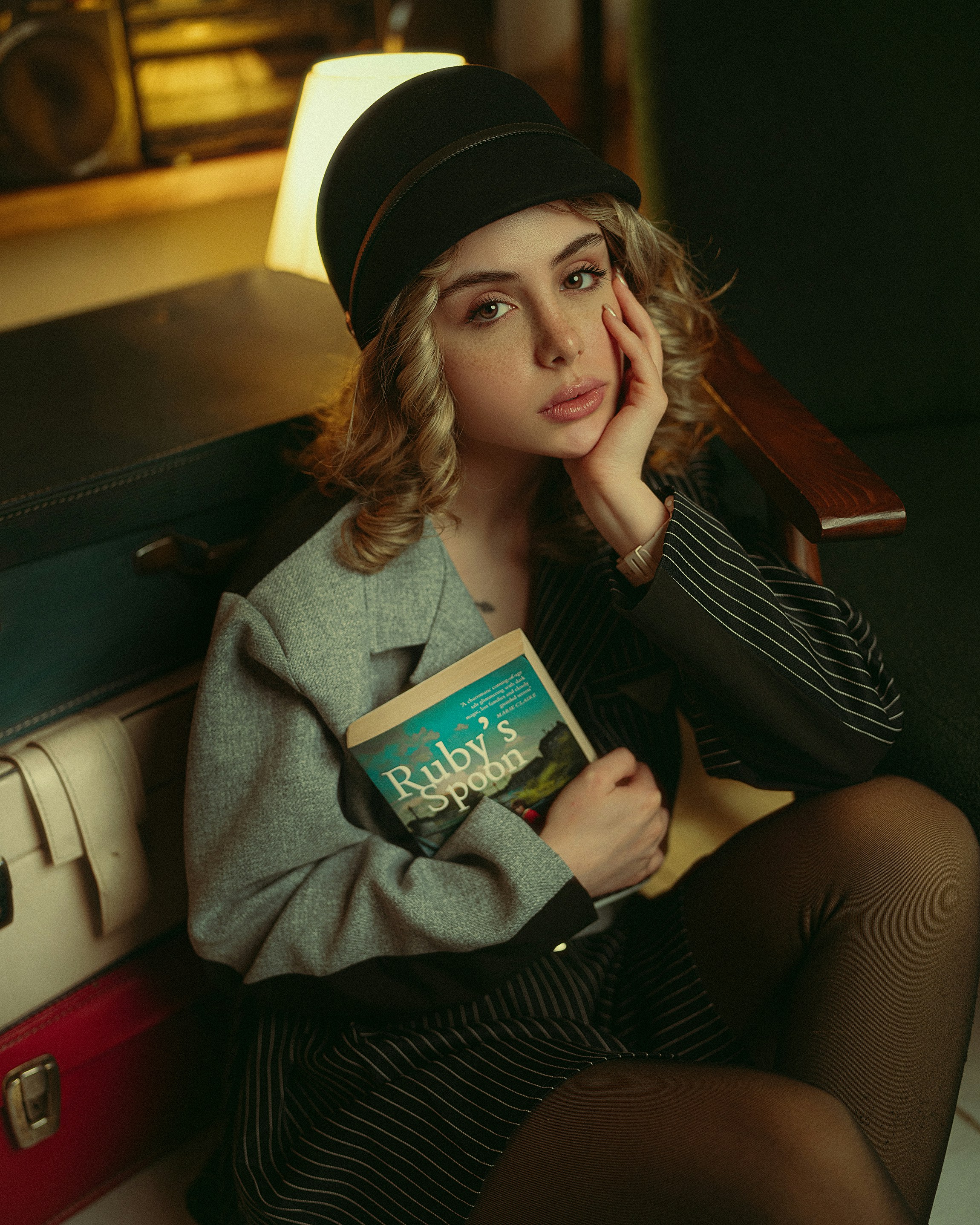 Femme au chapeau tenant un livre avec des bagages empilés