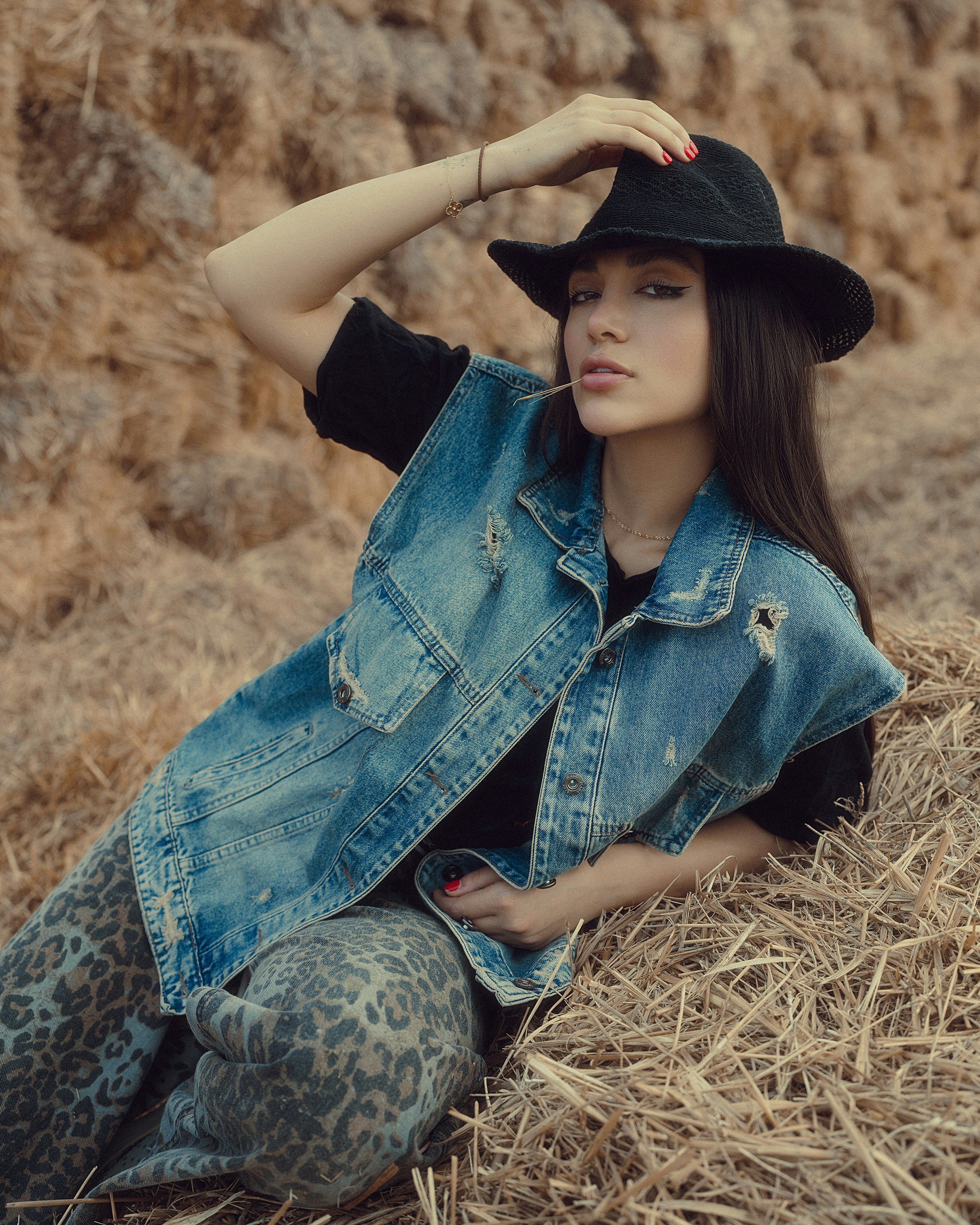 Femme en gilet en jean et chapeau sur balle de foin