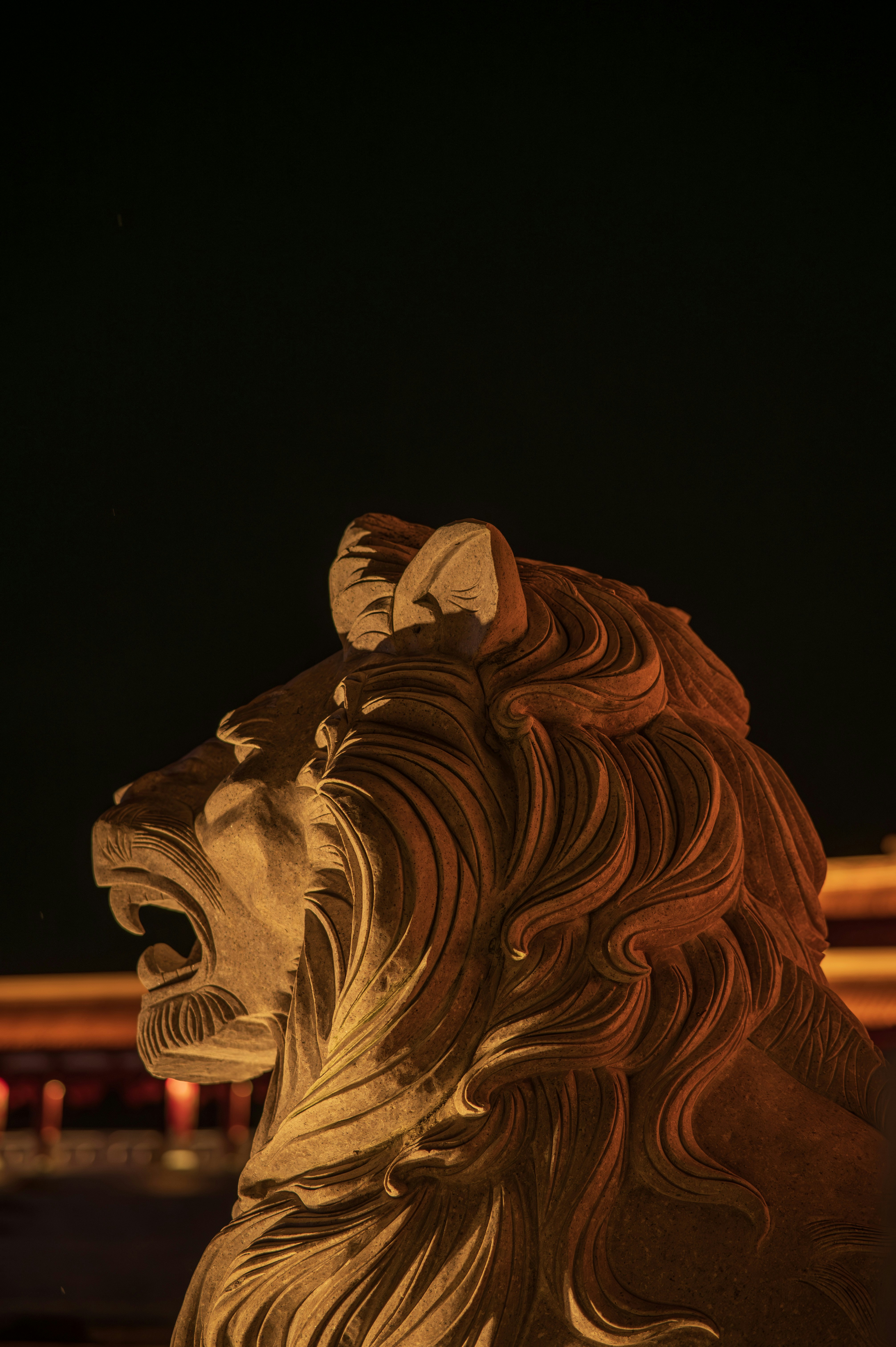 Golden lion statue with open mouth against dark background
