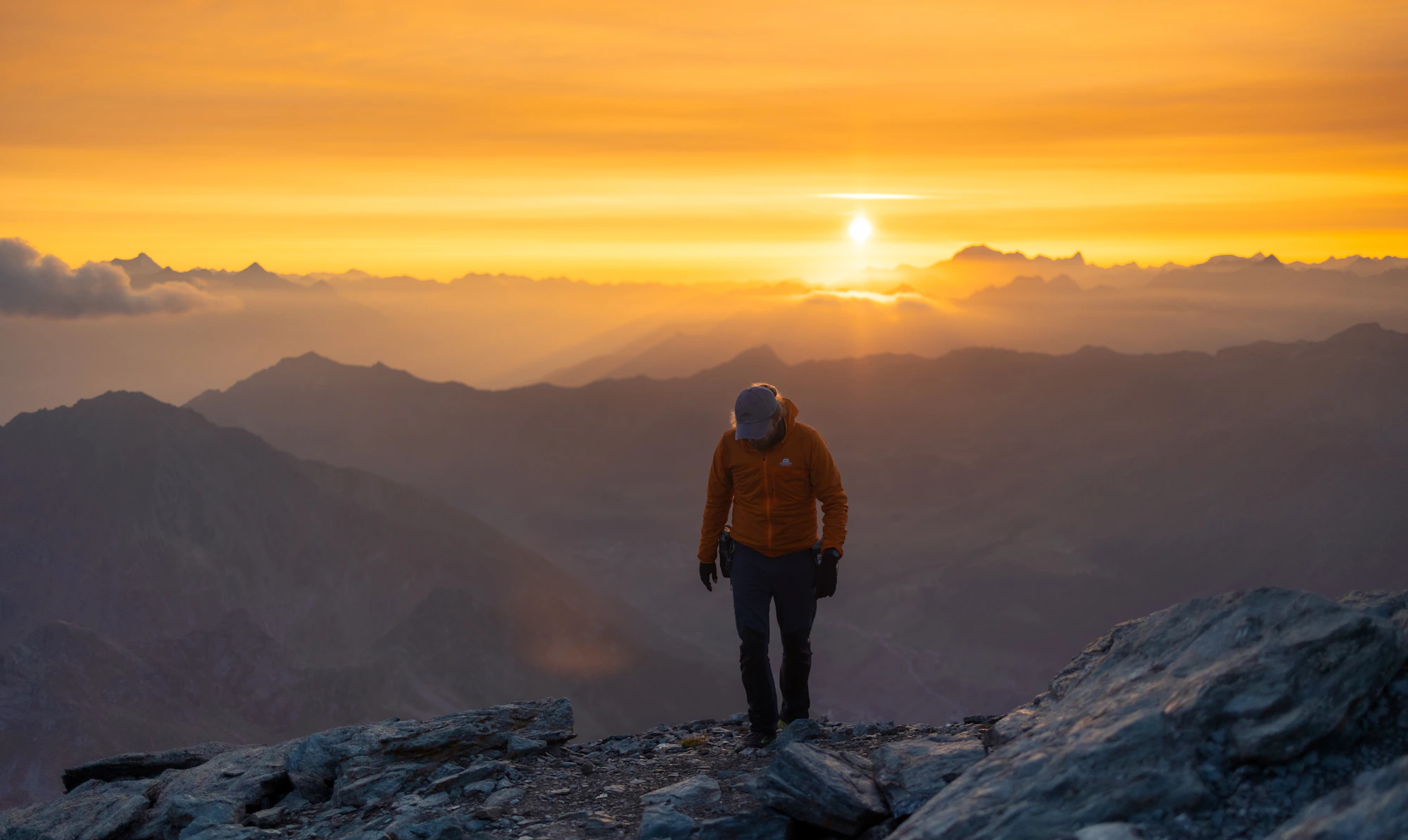 A hiker reaching a mountain summit at sunrise