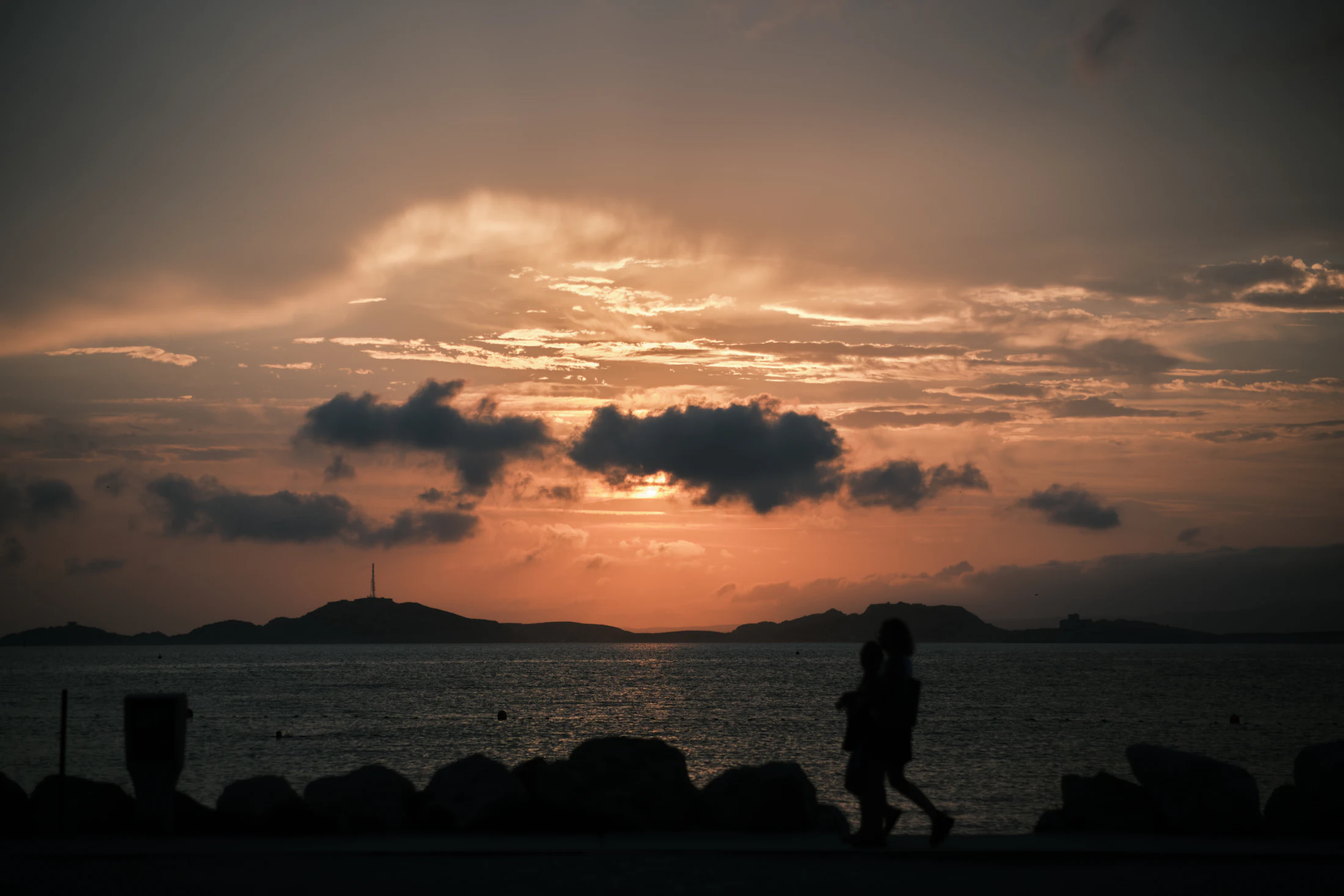 A couple walking together along the coast at sunset