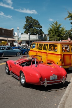 Red convertible sports car parked next to yellow woody wagon