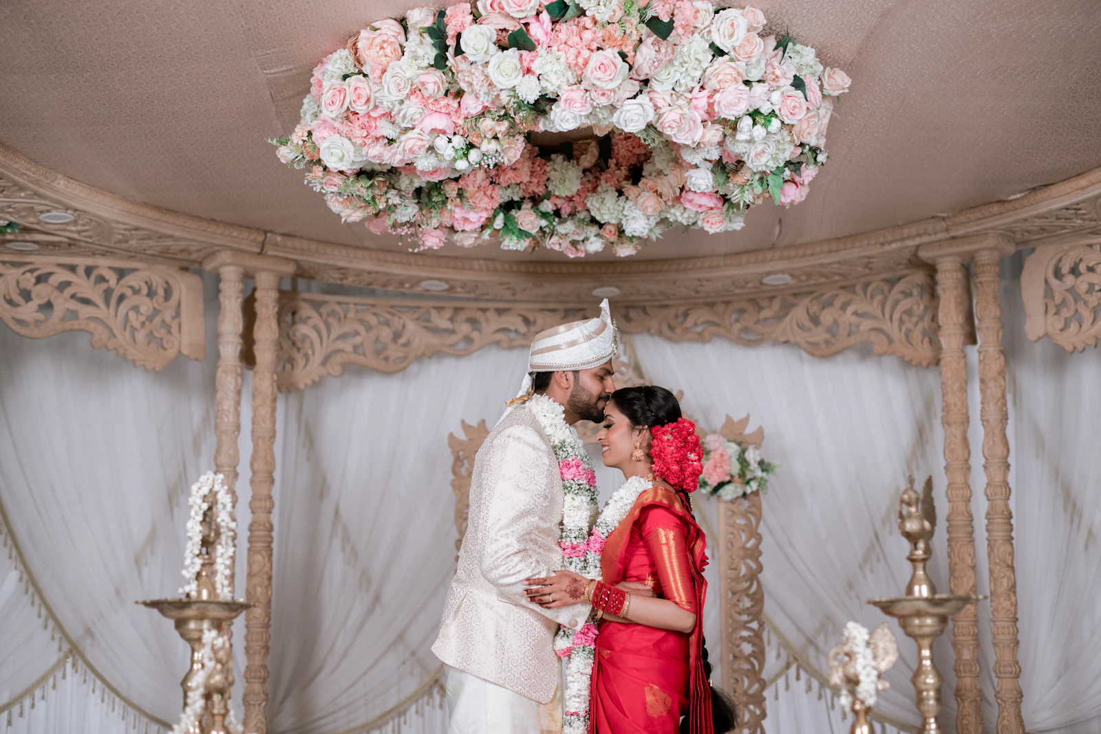A couple beneath a floral mandap.